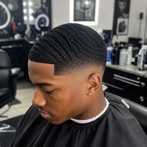 Professional barber shop client with sharp 360 waves and a clean taper fade haircut, featuring crisp lineup edges, detailed wave pattern, and a smooth low taper around the temples and neckline.
